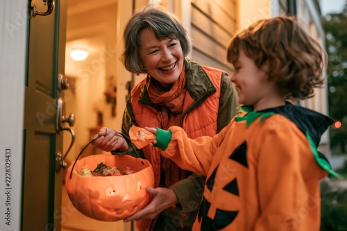 Grandmother giving candy to boy in pumpkin costume