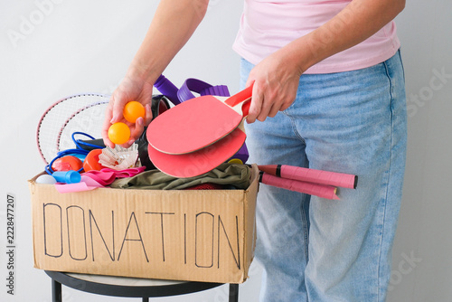 Donation box with sports equipment. The volunteer puts tennis rackets into a cardboard box.