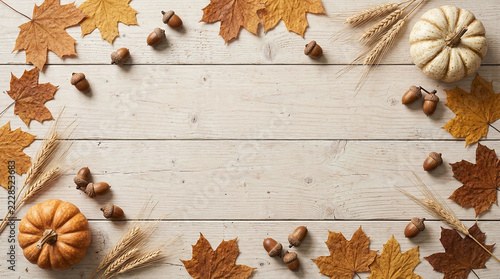 Autumn border frame made with pumpkins acorns and dried leaves on white wood