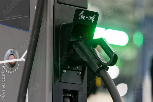 close-up of an electric vehicle charging plug in a charger station socket.