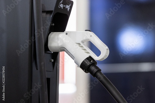 close-up of an electric vehicle charging plug in a charger station socket.