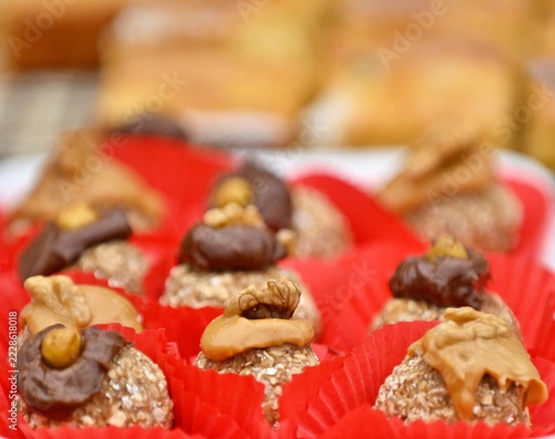 Bite-sized desserts topped with walnuts arranged in red liners.