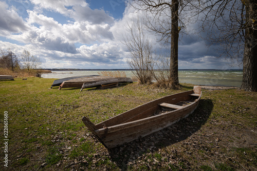 Old rural wooden, fishing boats is moored on the shore of a lake. A windy day