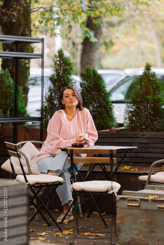 beautiful brunette woman in sunglasses is walking in the park with a cup of coffee
