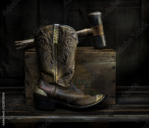 Old cowboy boot and old rubber mallet, with old wooden box in still life.