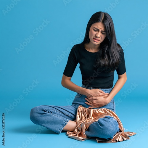 Young asian woman having her period holding her stomach in pain on isolated background 