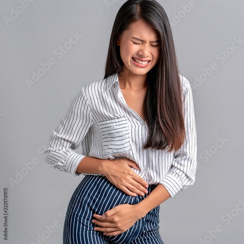 Young asian woman having her period holding her stomach in pain on isolated background 