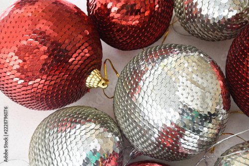 Top view of red and silver sequin Christmas baubles with sparkling glitter details, festive holiday decorations, elegant seasonal background, and shimmering metallic textures.