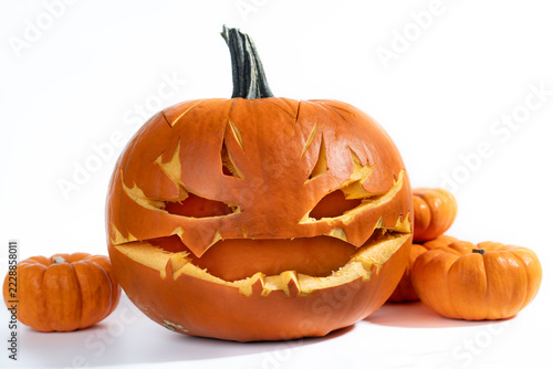A close-up of a hollowed-out pumpkin with a face carved into it. The background is white.