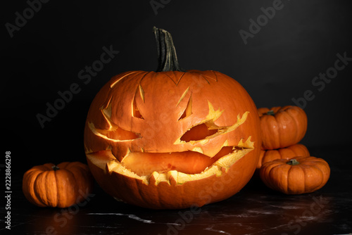 Close-up of a hollowed-out pumpkin with a face carved into it. The background is dark.