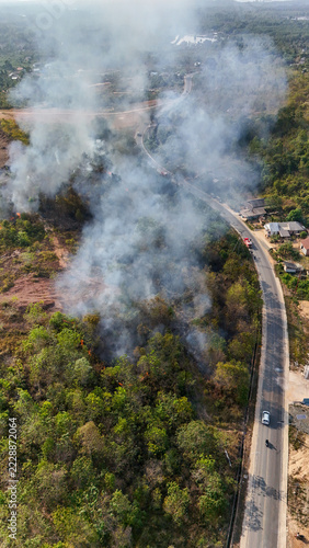 Aerial view of a forest fire burning near a road with thick smoke rising above the trees in Kotabaru, Kalimantan Selatan, Indonesia.