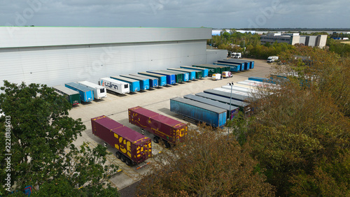 Aerial view of a logistics distribution center with numerous parked HGV trailers arranged in rows next to a large warehouse building in Magna Park, England, United Kingdom.