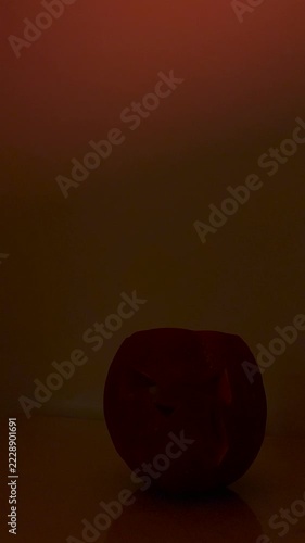 Carved Halloween pumpkin jack o lantern with scary face and changing red lighting in dark background. Spooky holiday atmosphere, mystery lighting shift, party decoration and horror concept