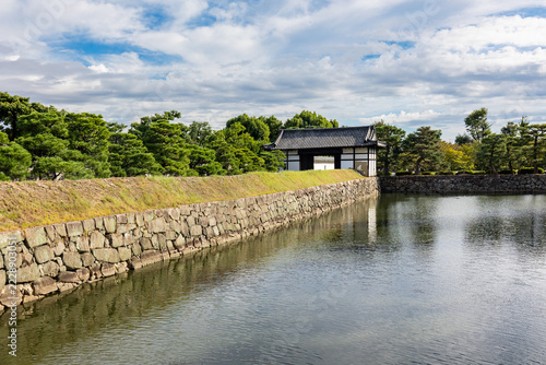Historic moat of Nijo Castle Kyoto with stone walls green trees and urban skyline in background, Kyoto, Japan 