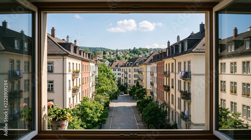 View from open window onto charming European residential street with trees and buildings in summer
