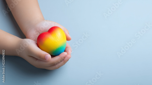 A child's hands gently holding a heart symbolize kindness and unconditional support for diversity and inclusion