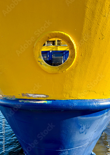 Porthole in a Yellow Ferry Bow Above a Blue Hull
