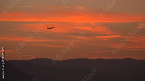 Airplane take of in sunset an wind turbine in background