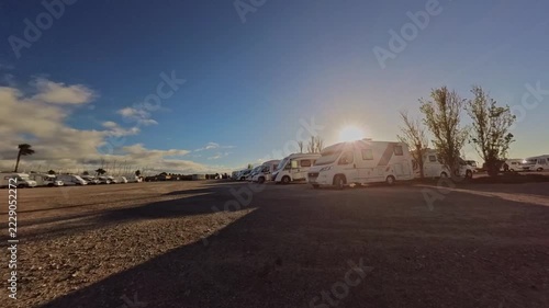 Time-lapse of a motorhome parking area at sunrise, showing RVs, changing light and long shadows under a beautiful evening sky.