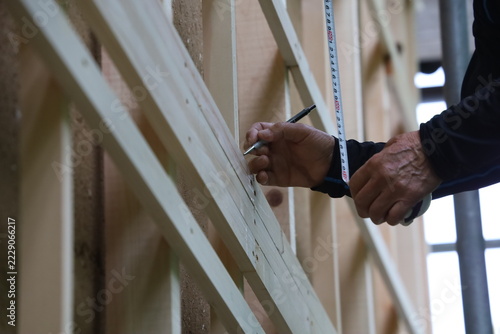 Worker's Hand Marking Measurement on Wooden Siding with Mechanical Pencil After Tape Measure