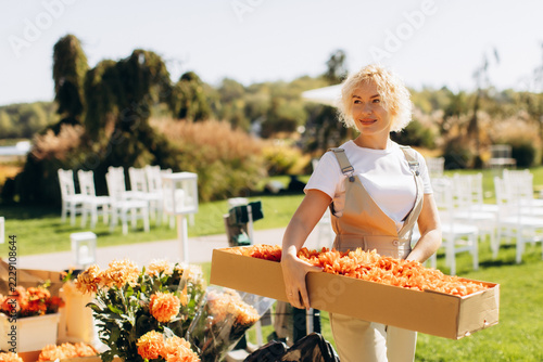 Florist preparing outdoor wedding event with orange flowers