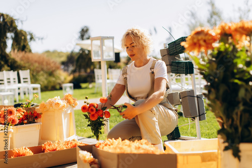 Florist arranging orange dahlia flowers for outdoor wedding