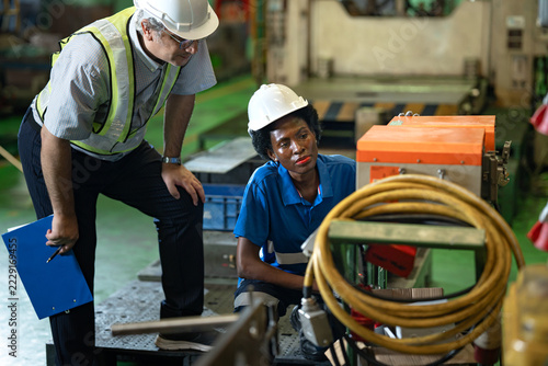 African woman electrician worker with manager engineer man checking, repair, maintaining battery for energy in industry factory