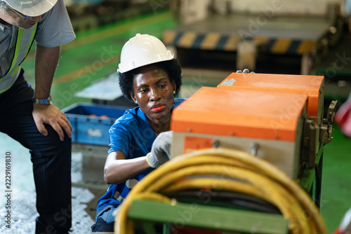 African woman electrician worker with manager engineer man checking, repair, maintaining battery for energy in industry factory
