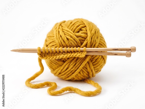 Bright yellow yarn ball with knitting needles creating stitches on transparent background