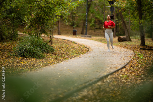 Obraz na plátně Woman running along winding park path in autumn
