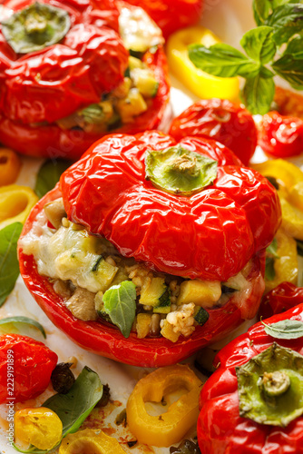 Baked stuffed red bell peppers  with oat groats with zucchini, mushrooms and melted cheese, roasted cherry tomatoes and basil, vertical