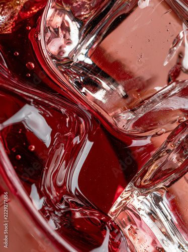 Macro shot of a melting ice cube in a ruby drink