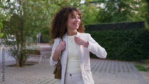 Cheerful businesswoman walking outdoors in a city park