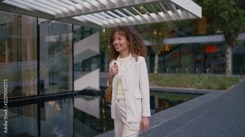 Smiling businesswoman walking outside modern office building