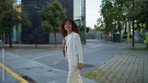 Elegant young businesswoman walking across city street smiling confidently