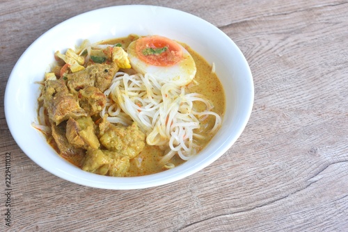 rice noodles in coconut milk curry soup with beef meat topping slice creamy     boiled egg yolk halal food on bowl