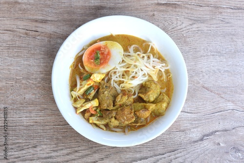 rice noodles in coconut milk curry soup with beef meat topping slice creamy     boiled egg yolk halal food on bowl