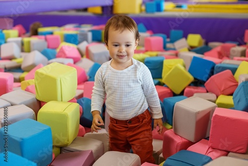 Smiling Toddler Standing in Colorful Foam Cube Pit at Indoor Trampoline Park