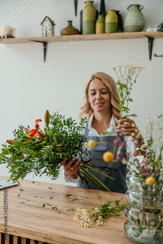 Florist woman creating fresh flower bouquet in workshop