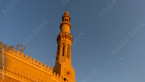 Mezquita El Tabia en Asuán , Egipto, con sus minaretes ornamentados y cúpula iluminados por el sol bajo un cielo azul intenso