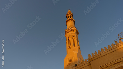 Mezquita El Tabia en Asuán , Egipto, con sus minaretes ornamentados y cúpula iluminados por el sol bajo un cielo azul intenso