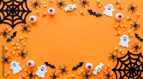 Halloween holiday background with candy and creepy decorations arranged in a frame