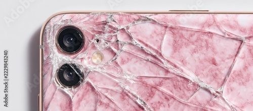 Close-up of a damaged electronic device with cracked glass over a pink marble design