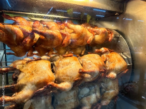 Roasted chicken rolling on stainless steel racks in the hot oven for food preparation and cooking concept