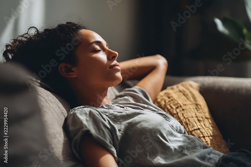relaxed woman resting on sofa at home with eyes closed. mental wellness, stress relief and self care lifestyle concept