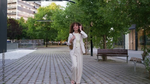 Smiling businesswoman walking along city street