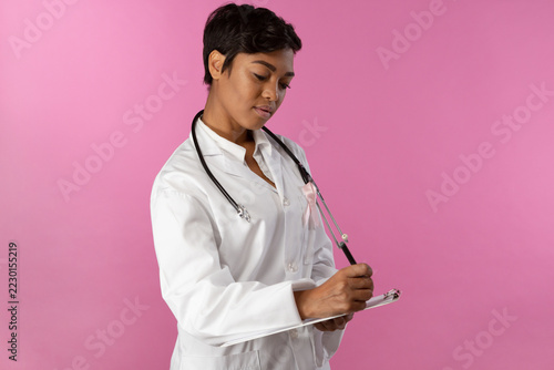 Writing nurse wearing breast cancer awareness pink ribbon
