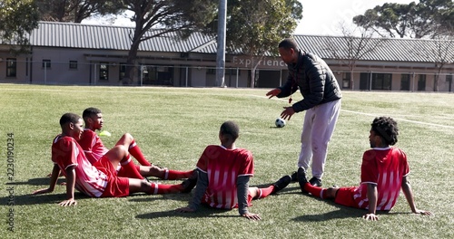 Soccer team celebrating victory with coach on school field, showing teamwork spirit