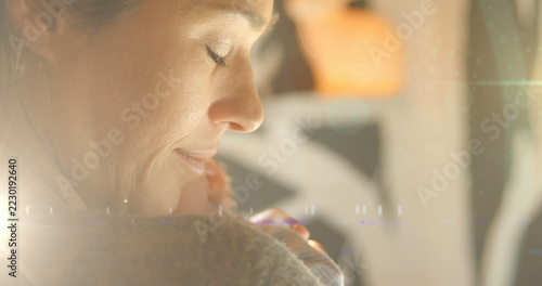 Image of glowing spots over happy caucasian mother with sleeping baby