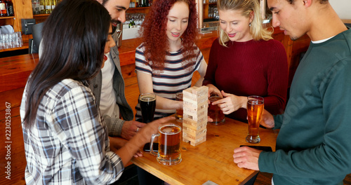 Friends enjoy a sociable game of Jenga over beers at a bar.